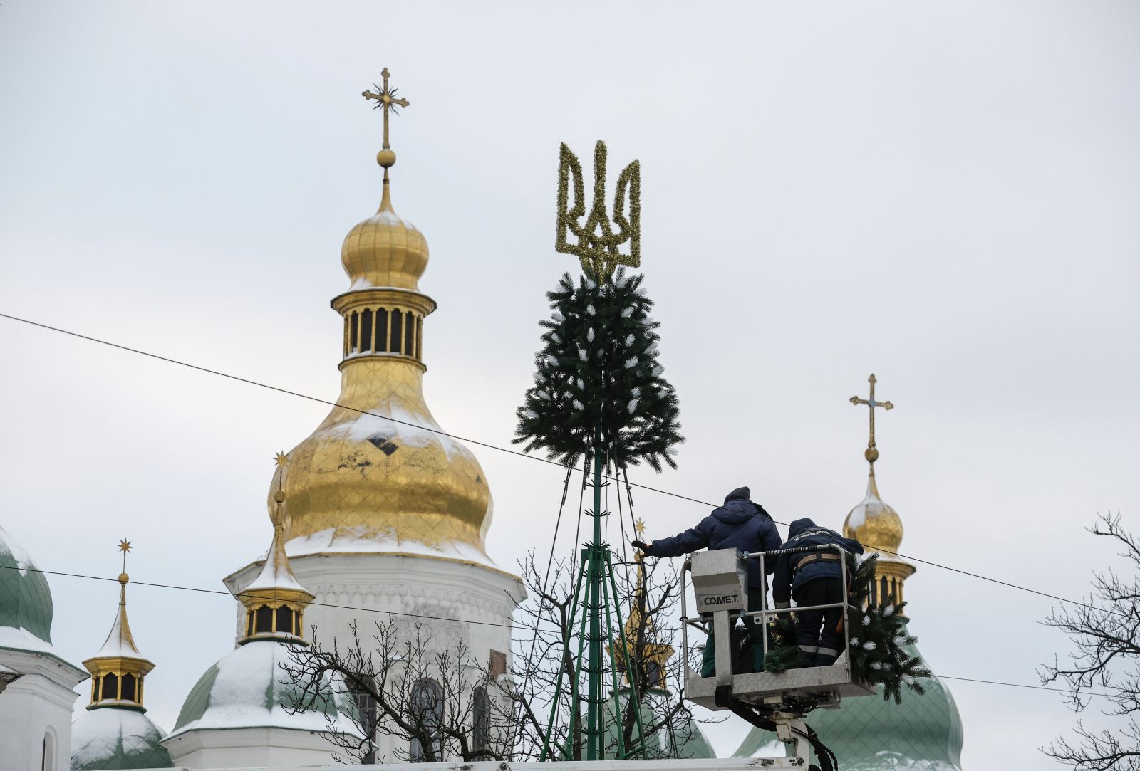epa11010824 Workers place the State emblem on top of a Christmas tree in front of Saint Sophia's Cathedral in Kyiv, Ukraine, 04 December 2023 This year Ukraine will mark Christmas on the 25 December together with Europe, unlike in previous years when Ukraine marked Christmas on 07 January with other post-Soviet countries. Russian troops entered Ukraine on 24 February 2022 starting a conflict that has provoked destruction and a humanitarian crisis.  EPA/SERGEY DOLZHENKO