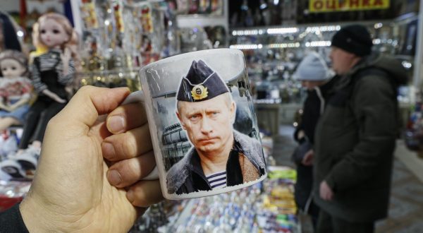 epa11015296 A person holds a cup with portrait of Russian President Vladimir Putin in a gift shop in downtown Moscow, Russia, 07 December 2023. The Federation Council adopted a resolution calling for a presidential election to be held on 17 March 2024.  EPA/YURI KOCHETKOV