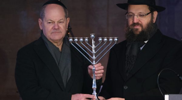 epa11015698 German Chancellor Olaf Scholz (L) receives a Menorah from Chairman of the Jewish Education Center Chabad Rabbi Yehuda Teichtal (R) during the lighting ceremony in front of a Hanukkah Menorah near the Brandenburg Gate in Berlin, Germany, 07 December 2023. Hanukkah, also known as the 'Festival of Lights', is one of the most important Jewish holidays and is celebrated by Jews worldwide.  EPA/CLEMENS BILAN