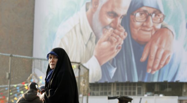 epa11053650 An Iranian woman walks past a huge billboard showing the late Iran's Islamic Revolutionary Guard Corps (IRGC) Quds Force commander Qasem Soleimani kissing his mother's hand in the Vali-Asr square ahead of his fourth death anniversary, in Tehran, Iran, 02 January 2024. Iranians will mark the anniversary of Soleimani's death on 03 January 2024. Soleimani was killed on 03 January 2020 in a targeted US airstrike at the Baghdad airport in Iraq.  EPA/ABEDIN TAHERKENAREH