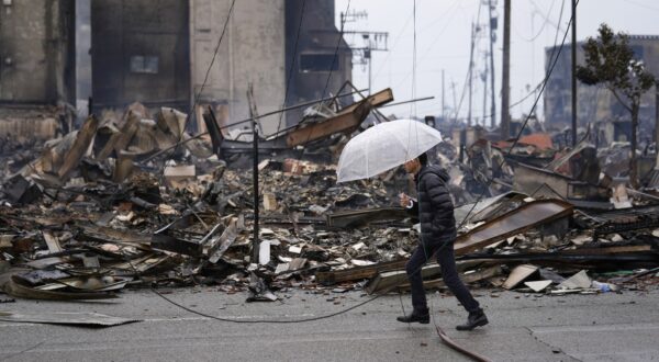 epa11054882 A man walks past burnt remains of building structures following an earthquake in Wajima, Ishikawa Prefecture, Japan, 03 January 2024. At least 62 people were killed by the magnitude 7 earthquake (the USGS listed the magnitude as 7.5) which occurred on 01 January, according to the Ishikawa Prefecture Government.  EPA/FRANCK ROBICHON