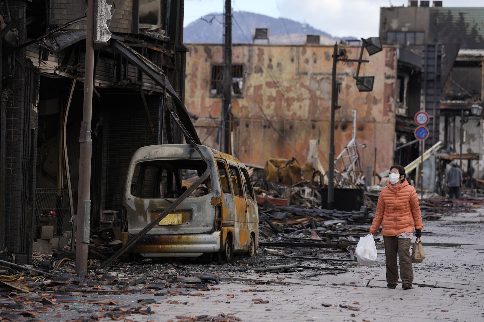 epa11056363 A woman looks at the burnt remains of a vehicle and building structures following an earthquake in Wajima, Ishikawa Prefecture, Japan, 04 January 2024. The Ishikawa Prefecture Government announced that 78 people were killed and 25 missing following a magnitude 7 earthquake (the USGS listed the earthquake as 7.5 magnitude) which occurred on 01 January. About 33,000 residents in Ishikawa Prefecture have evacuated to 355 makeshift evacuation centers. According to Hokuriku Electric Power Company, about 33,900 homes lost electricity in the prefecture.  EPA/FRANCK ROBICHON