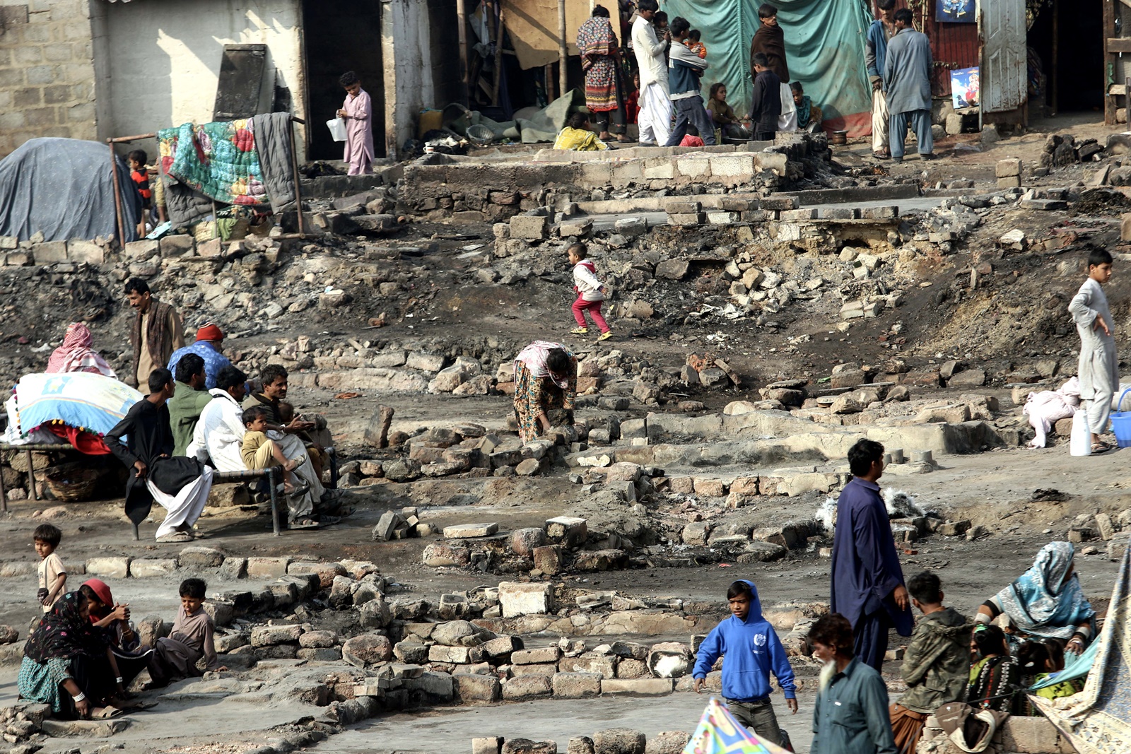 epa11058682 People are seen at a damaged area after a fire broke out in the slums beneath the Teen Hatti Bridge, engulfing more than 15 huts, in Karachi, Pakistan, 05 January 2024. While over 100 huts suffered damage, no loss of life has been reported, officials said. The fire is under control and the cooling process is underway as fire brigades and police were deployed to the area.  EPA/REHAN KHAN