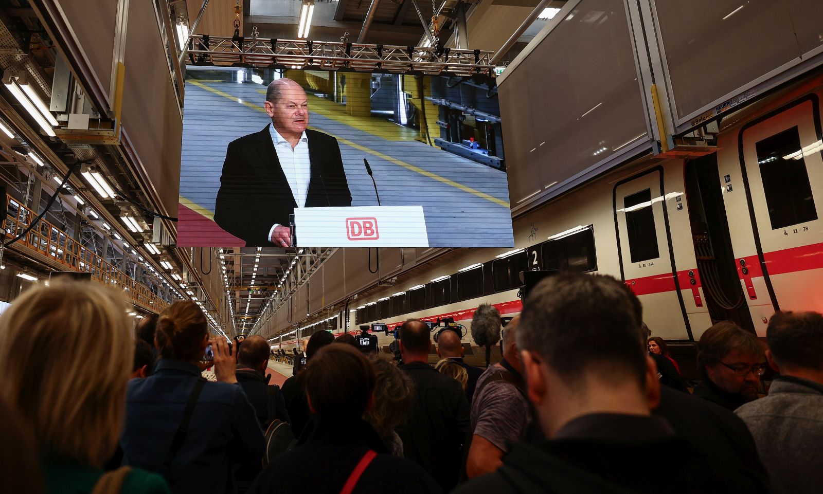 epa11068960 German Chancellor Olaf Scholz is seen on a screen as he speaks at the opening ceremony of the new Deutsche Bahn ICE4 express train plant in Cottbus, Germany, 11 January 2024. New ICE factory will help Deutsche Bahn's to increase the number of rapidly growing ICE 4 fleet and test new technologies as DB is planning to increase the number of long-distance passengers to 260 million per year by 2030.  EPA/FILIP SINGER
