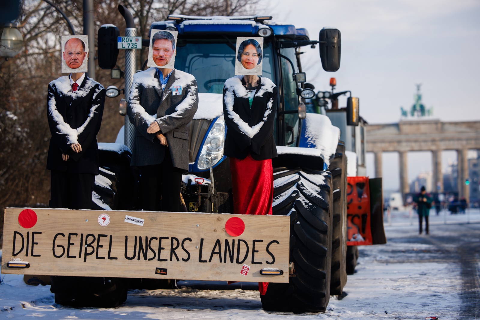 epa11087923 A tractor is decorated with mannequins with photos of German Chancellor Olaf Scholz (L), German Minister for Economy and Climate Robert Habeck (C) and German Foreign Minister Annalena Baerbock (R) during a protest of truckers in Berlin, Germany, 18 January 2024. The wooden board reads 'The scourge of our country.' Farmers in Germany went on a nationwide strike to protest the federal government's agricultural policies. Later, truckers joined the recent protests in support of the farmers.  EPA/CLEMENS BILAN