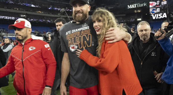 FILE - Kansas City Chiefs tight end Travis Kelce walks with Taylor Swift following the AFC Championship NFL football game between the Baltimore Ravens and the Kansas City Chiefs, Sunday, Jan. 28, 2024, in Baltimore. As the Kansas City Chiefs head to the Super Bowl, baseless conspiracy theories are spreading on social media suggesting that the romance between megastar Taylor Swift and Kansas City Chiefs tight end Travis Kelce is part of a secret plot to help President Joe Biden get reelected in 2024. (AP Photo/Julio Cortez, File)