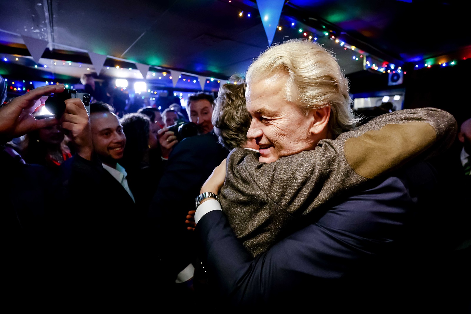 epa10990069 PVV leader Geert Wilders (R) is hugged as he responds to the results of the House of Representatives elections in Scheveningen, Netherlands, 22 November 2023. Dutch voters headed to the polls on 22 November to elect the members of the House of Representatives and a new prime minister, after Netherlands' longest-serving prime minister, Mark Rutte's cabinet collapsed in July.  EPA/REMKO DE WAAL