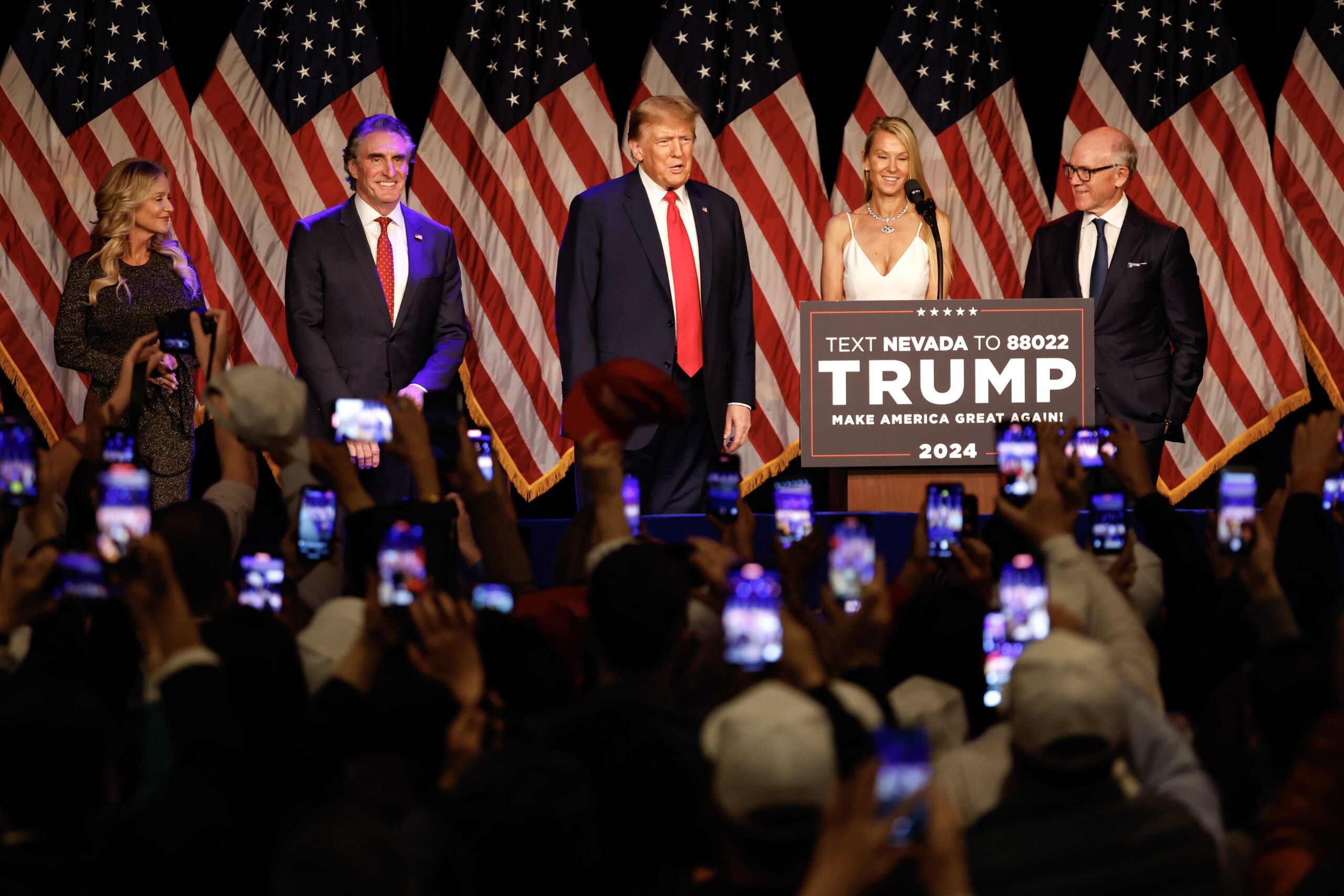 epa11138593 Republican presidential candidate and former US president Donald J. Trump (C) acknowledges his supporters as Republican Governor of North Dakota, Doug Burgum (2-L), his wife Kathryn Helgaas Burgum (L) and New York Jets owner Woody Johnson (R) look on during Trump's campaign hosted caucus night watch party event at the Treasure Island Resort & Casino in Las Vegas, Nevada, USA, 08 February 2024.  EPA/JOHN MABANGLO