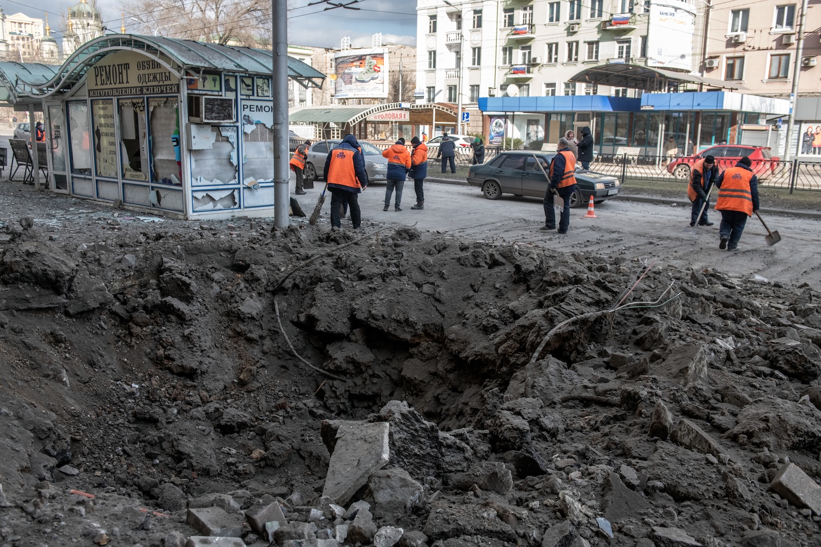 epa11168095 Municipal workers clean a street next to a shelling crater in the aftermath of a shelling in downtown Donetsk, Russian-controlled Ukraine, 20 February 2024. A woman was killed and dozens were injured in the shelling of Kievsky and Voroshilovsky districts of Donetsk, according to city Mayor Alexey Kulemzin.  EPA/VALERY MELNIKOV