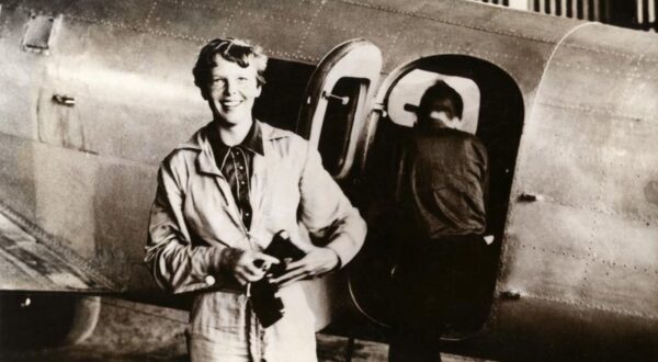 Amerikaanse pilote / vliegenier Amelia Earhart (1897-1937) in vliegoverall bij een vliegtuig. Zonder plaats, [1937 of eerder].

American aviator/pilot Amelia Earhart (1897-1937) standing by a plane dressed in overalls. Location unknown.