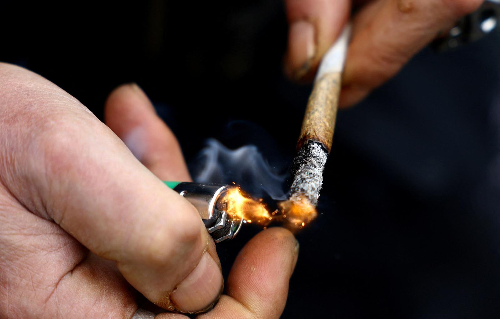 FILE PHOTO: A person lights a joint as marijuana activists gather to mark the annual world cannabis day and to protest for legalization of marijuana, in front of the Brandenburg Gate, in Berlin, Germany, April 20, 2022. REUTERS/Lisi Niesner/File Photo Photo: LISI NIESNER/REUTERS