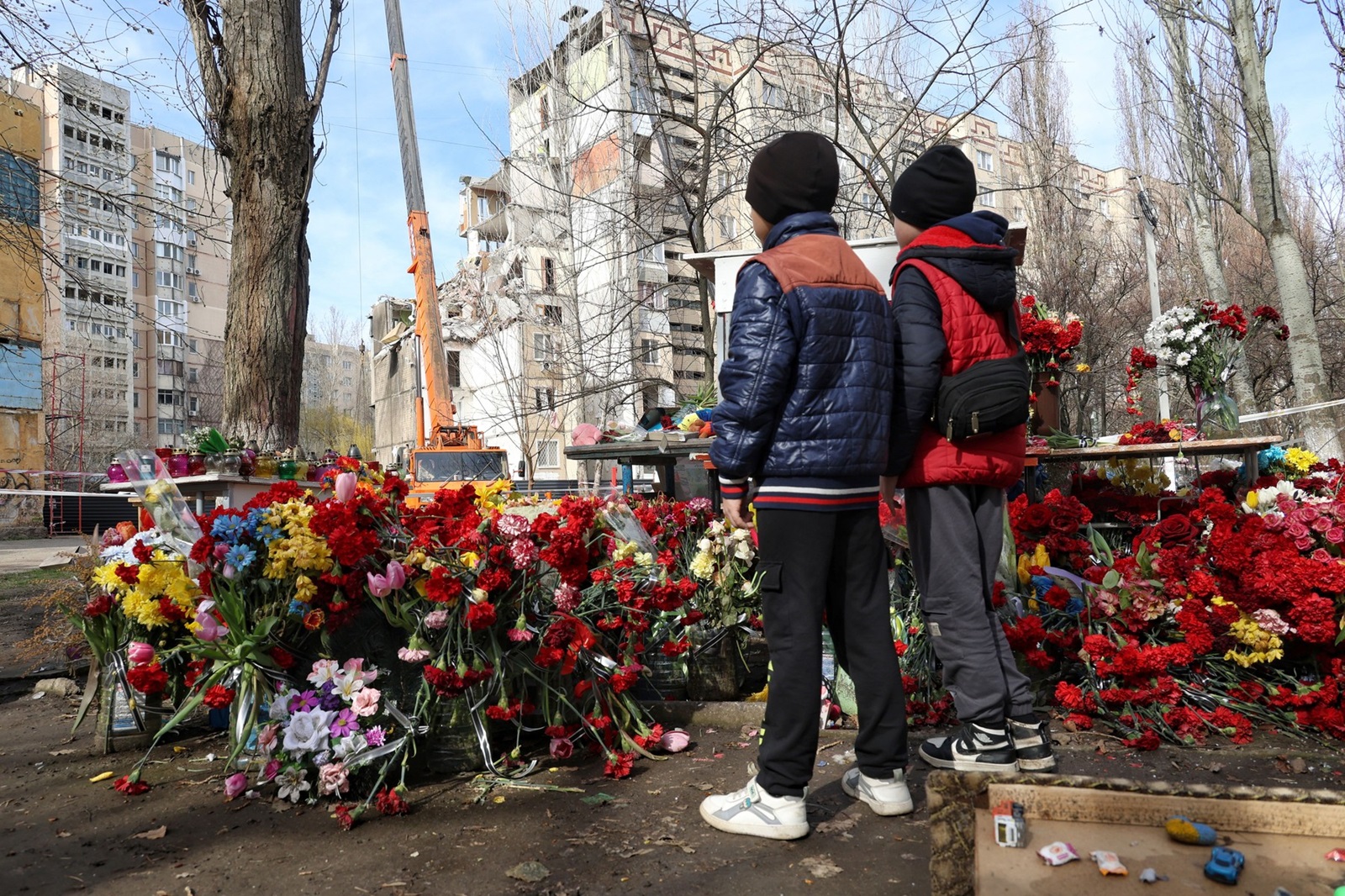 Non Exclusive: ODESA, UKRAINE - MARCH 27, 2024 - Boys stand by the heaps of flowers brought by people to the site of the tragedy as part of the section of a 9-story residential building on Dobrovolskoho Avenue collapsed, hit by a Russian drone on March 2, the dismantling works are underway, Odesa, southern Ukraine.,Image: 860480439, License: Rights-managed, Restrictions: This photo cannot be distributed in the Russian Federation. MANDATORY CREDIT OR DOUBLE FEE WILL BE CHARGED - **Strictly no use in repeat online galleries without payment**, Model Release: no, Credit line: / BEEM / Beem / Profimedia