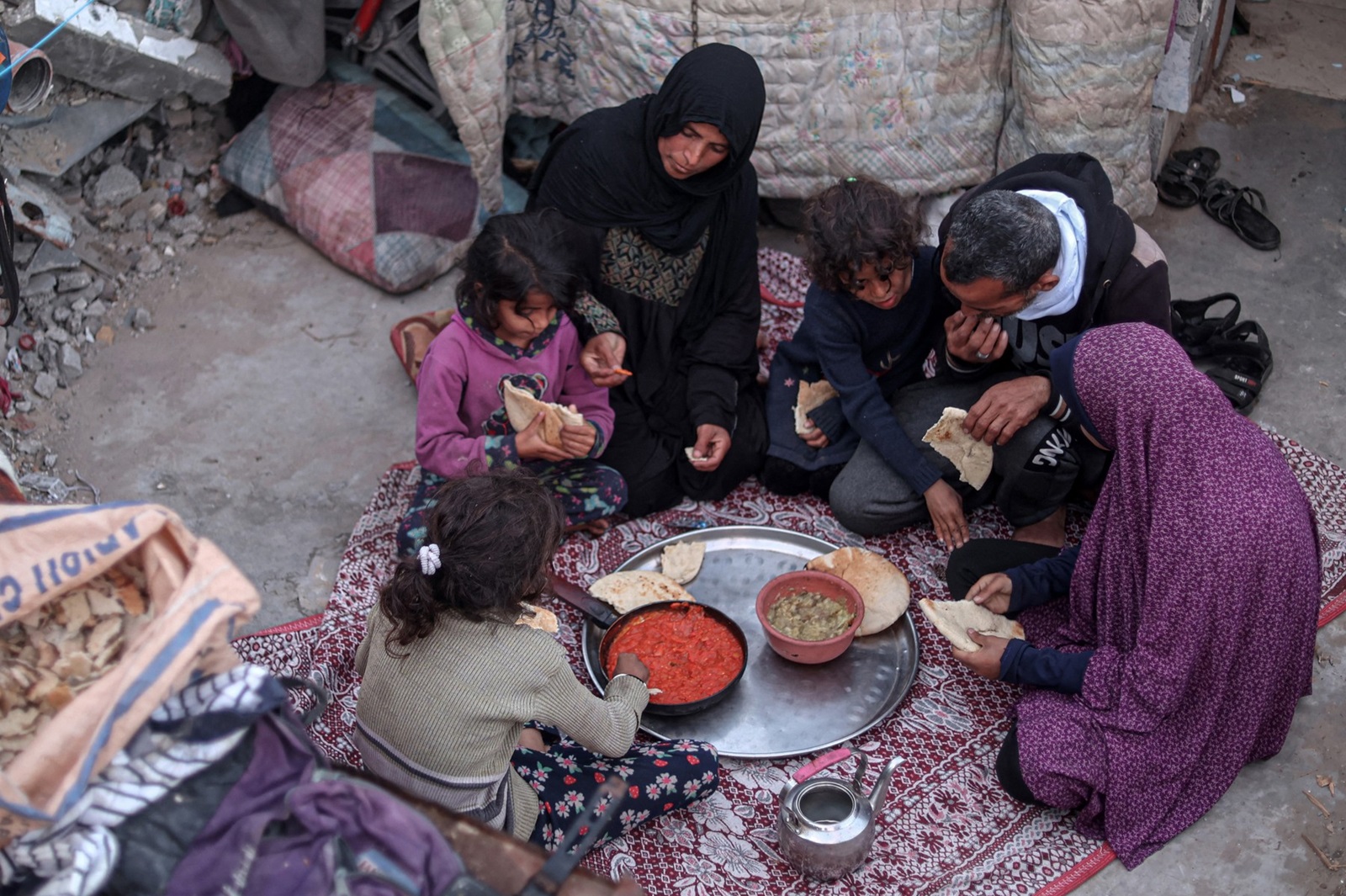 Members of the Rabaya family break their fast amidst the rubble of their home, which was destroyed by an Israeli strike, during the Muslim holy month of Ramadan in Rafah on March 23, 2024, amid ongoing battles between Israel and the militant group Hamas.,Image: 859035942, License: Rights-managed, Restrictions: , Model Release: no, Credit line: SAID KHATIB / AFP / Profimedia