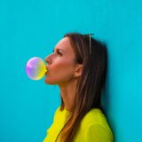 Portrait of young beautiful lady in yellow t-shirt standing isolated on turquoise background wall while blowing bubble with colourful chewing gum. High quality photo,Image: 549353114, License: Royalty-free, Restrictions: , Model Release: no, Credit line: Daria Kulkova / Alamy / Alamy / Profimedia