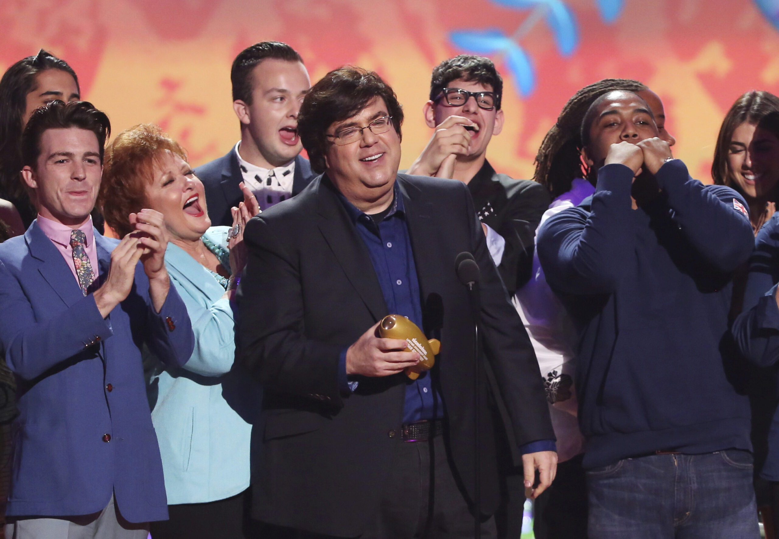 FILE - In this March 29, 2014, file photo, Dan Schneider, center, accepts the lifetime achievement award at the 27th annual Kids' Choice Awards at the Galen Center in Los Angeles. Nickelodeon is breaking ties with Schneider, the creator of some of its top shows, including “Henry Danger” and “iCarly.” In a joint statement, Nickelodeon, Schneider and his production company, Schneider’s Bakery, agreed it “is a natural time” to pursue other opportunities and projects since several Schneider’s Bakery projects are wrapping up. (Photo by Matt Sayles/Invision/AP, File)