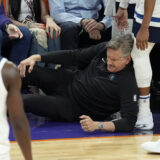Minnesota Timberwolves head coach Chris Finch holds his knee after colliding with Timberwolves guard Mike Conley during the second half of Game 4 of an NBA basketball first-round playoff series against the Phoenix Suns Sunday, April 28, 2024, in Phoenix. The Timberwolves won 122-116, taking the series 4-0. (AP Photo/Ross D. Franklin)