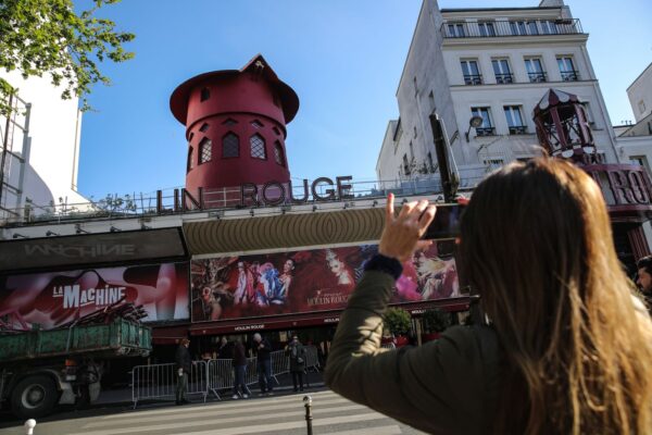 epa11299325 People stop to take photos of the facade of the Moulin Rouge without its wings in Paris, France, 25 April 2024. During the night of 24 to 25 April, the blades of the Moulin Rouge collapsed without causing any casualties, according to official sources.  EPA/Teresa Suarez