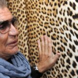 Italian designer Roberto Cavalli touches one of his prints during a press conference presenting his photography exhibition 