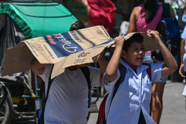Students use a cardboard to protect themselves from the sun during a hot day in Manila on April 2, 2024.  More than a hundred schools in the Philippine capital shut their classrooms on April 2, as the tropical heat hit 
