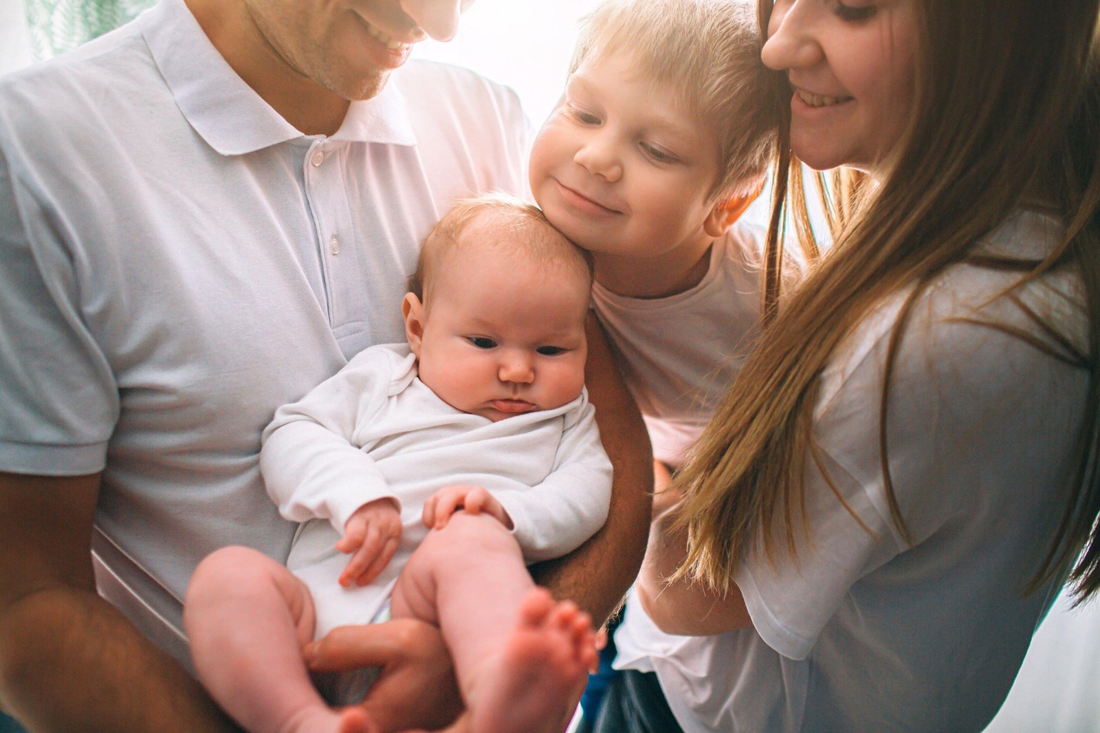 Mother and father are holding a baby in their arms. Big brother hugs his sister. Care and health. Happy young family.,Image: 516296696, License: Royalty-free, Restrictions: , Model Release: yes, Credit line: Vlad Dmytrenko / Alamy / Alamy / Profimedia