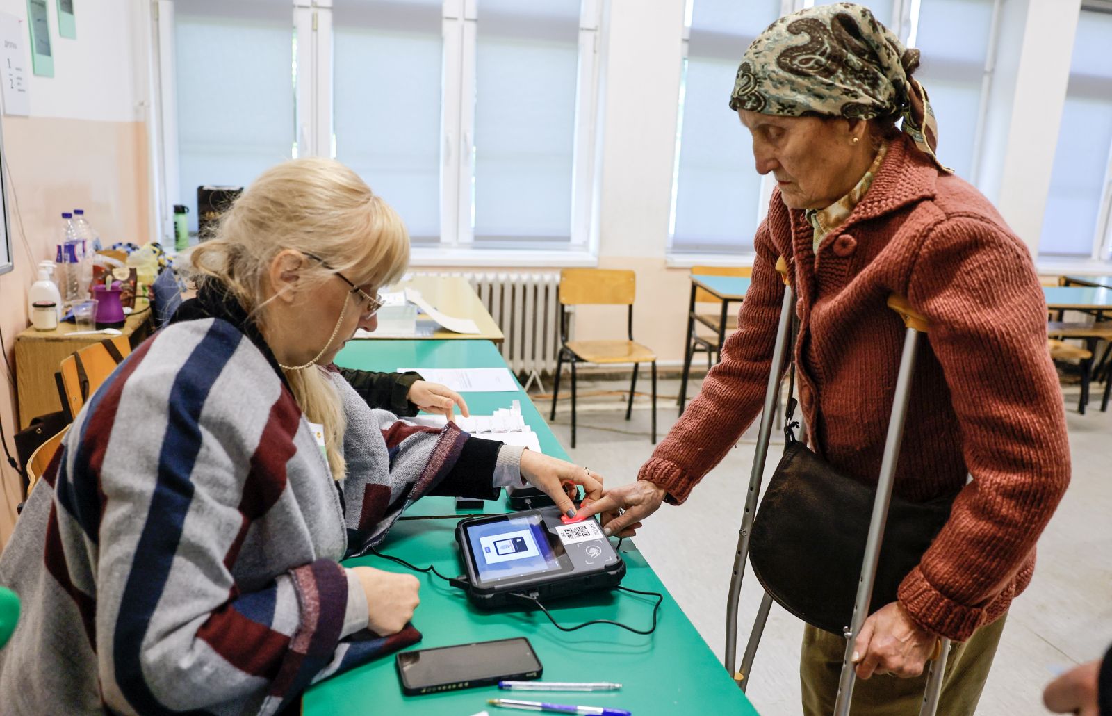 epa11297157 An election official runs a fingerprint authentication of an elderly woman during the first round of the presidential elections, at a polling station in Skopje, North Macedonia, 24 April 2024. More than 1.8 million registered voters are expected to choose between seven presidential candidates running for the largely ceremonial position in the first round of the country's presidential election held on 24 April.  EPA/GEORGI LICOVSKI