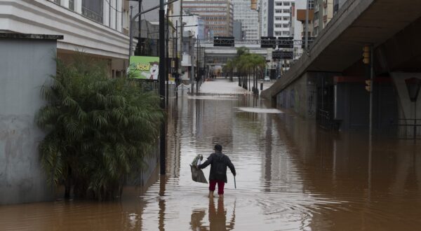 epa11316996 A man wades in a flooded street in the center of Porto Alegre, Brazil, 03 May 2024. Regional authorities reported that at least 37 people died and 60 are missing as a result of heavy rains that have affected the Brazilian state of Rio Grande do Sul in recent days. Due to the magnitude of the tragedy, the governor of the state, Eduardo Leite, decreed a state of public calamity for a period of 180 days throughout Rio Grande do Sul.  EPA/ISAAC FONTANA