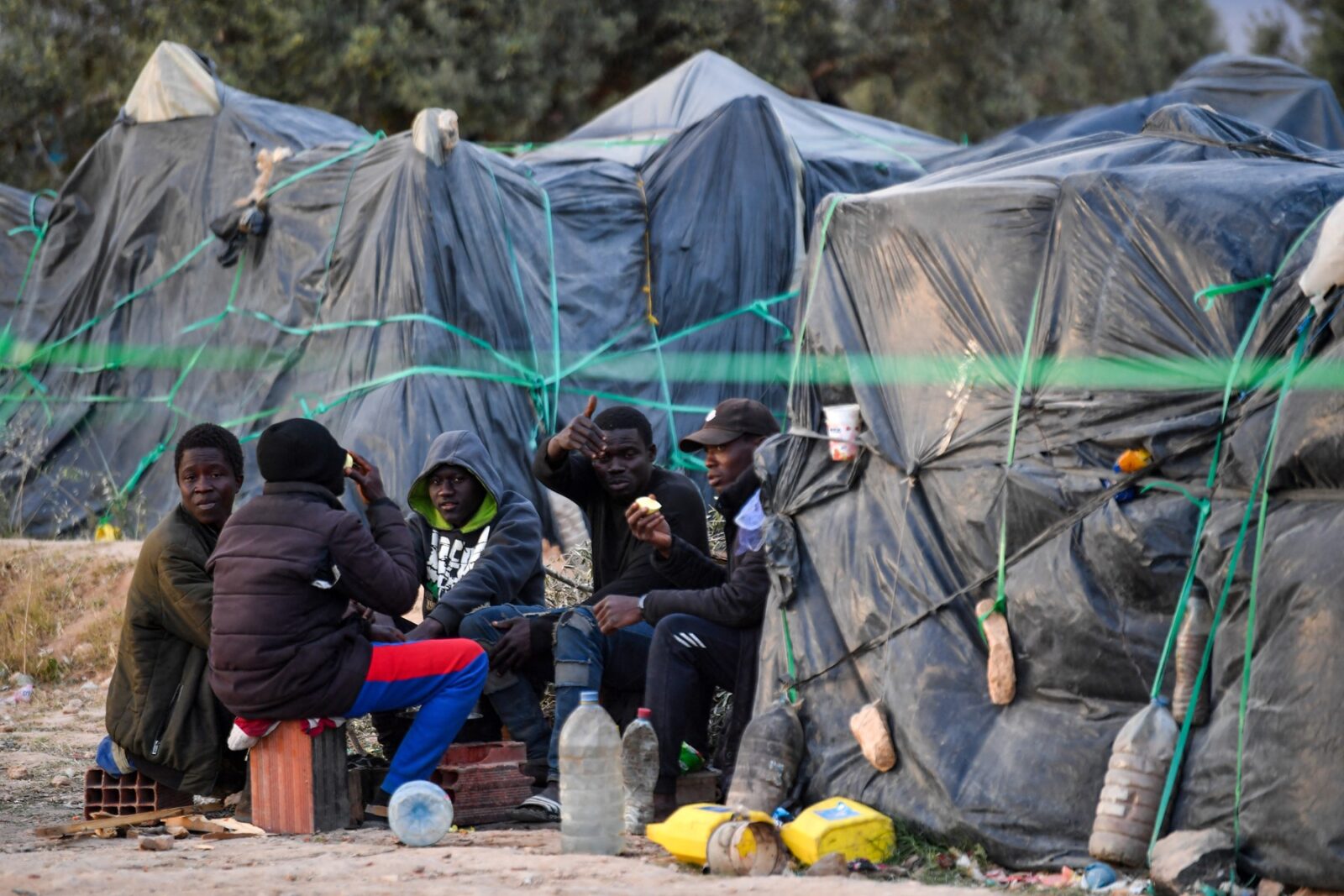 Migrants from sub-Saharan Africa sit next to makeshift shelters at a camp al-Amra on the outskirts of the Tunisian port city of Sfax on April 23, 2024. After President Kais Saied said in a speech last year that "hordes of illegal migrants" posed a demographic threat to Tunisia, anti-migrant violence broke out and hundreds of sub-Saharan Africans were kicked out of their jobs and homes.,Image: 867348527, License: Rights-managed, Restrictions: TO GO WITH: Tunisia-migration-rights FOCUS by Francoise KADRI, Model Release: no, Credit line: Fethi Belaid / AFP / Profimedia