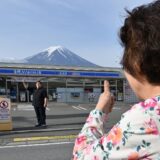 A person takes pictures of Mount Fuji from across the street of a convenience store, hours before the installation of a barrier to block the sight of Japan's Mount Fuji to deter badly behaved tourists, in the town of Fujikawaguchiko, Yamanashi prefecture on May 21, 2024. The plan to erect a large mesh barrier across the road from an Instagram-famous view of Mount Fuji made headlines last month when it was announced by officials fed up with what locals said were unending streams of mostly foreign visitors littering, trespassing and breaking traffic rules.,Image: 875012973, License: Rights-managed, Restrictions: , Model Release: no, Credit line: Kazuhiro NOGI / AFP / Profimedia