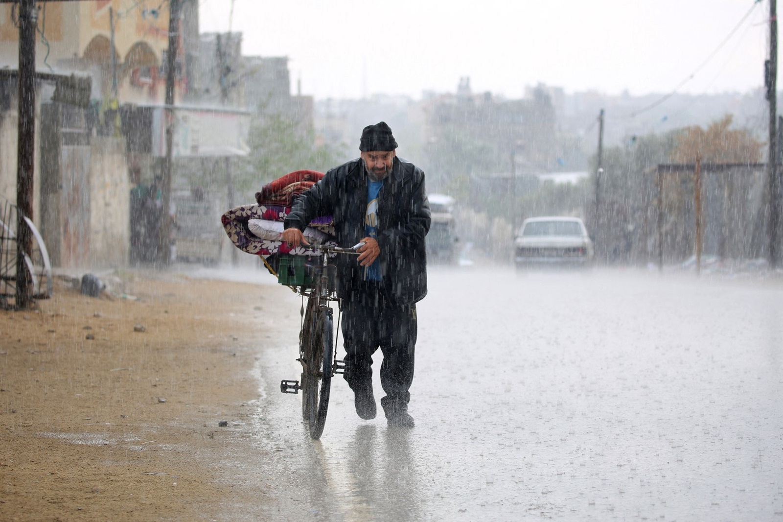 A displaced Palestinian man pushes a bycicle bearing his belongings in the rain in Rafah in the southern Gaza Strip following an evacuation order by the Israeli army on May 6, 2024, amid the ongoing conflict between Israel and the Palestinian Hamas movement.,Image: 870590635, License: Rights-managed, Restrictions: , Model Release: no, Credit line: AFP / AFP / Profimedia